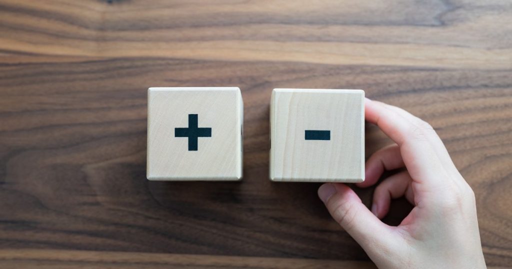 木製のブロックに描かれたプラス記号とマイナス記号。加点と減点を象徴するイメージ